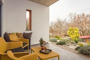 eine Terrasse mit gelben Stühlen und einem Tisch in der Unterkunft BIJOU house with apartments in Vilanija