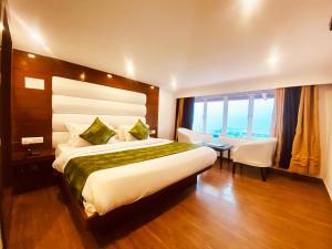 a hotel room with a large bed and a table at Hotel Royal Classic @ Mall Road Mussoorie in Mussoorie