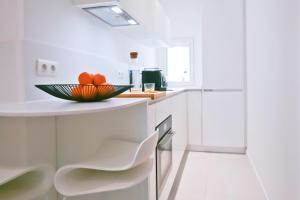 a white kitchen with a bowl of fruit on a counter at Studio cozy sur la Marina de Bonifacio in Bonifacio +5 photos