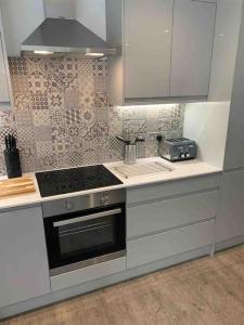a kitchen with white cabinets and a stove top oven at Beautiful cosy rural retreat with parking! in Winford