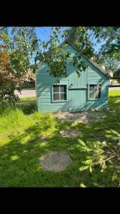 a blue house in the middle of a yard at Beautiful cosy rural retreat with parking! in Winford