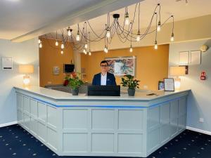 a man is standing behind a counter in a waiting room at Tiverton Hotel Lounge & Venue in Tiverton