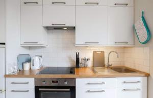 a kitchen with white cabinets and a sink at Lovely One Bed Apartment in Guildford in Guildford