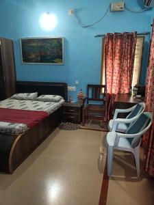 um quarto com uma cama, uma secretária e uma cadeira em Tavaru home stay em Ankola