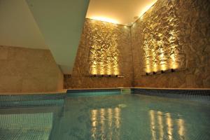 a swimming pool in a room with a stone wall at Garden Spa Boutique Hotel in Skopje