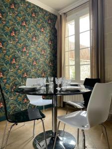 comedor con mesa y sillas y papel pintado con motivos florales en Gîte les Remparts, en Pierrefonds