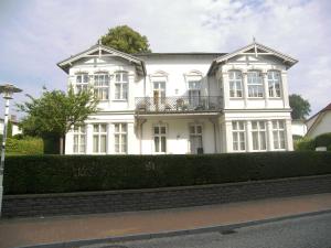 ein weißes Haus mit Balkon auf einer Hecke in der Unterkunft Villa Baroni nur 200m vom Ostseestrand entfernt in Bansin