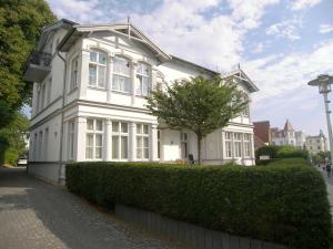 ein weißes Haus mit einem Baum davor in der Unterkunft Villa Baroni nur 200m vom Ostseestrand entfernt in Bansin