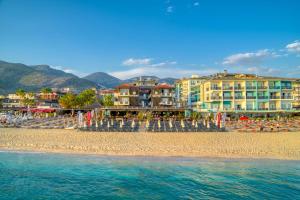 a beach with buildings and umbrellas and the water at Royalisa Palmiye Beach Hotel Adult Only in Alanya