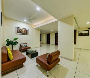 a living room with two chairs and a couch at Hotel Galaxy Inn Kolhapur in Kolhapur