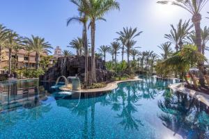 
a large swimming pool surrounded by palm trees at Lopesan Costa Meloneras Resort & Spa in Meloneras

