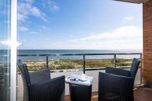 a balcony with two chairs and a table with a view of the ocean at Wattenblick in List