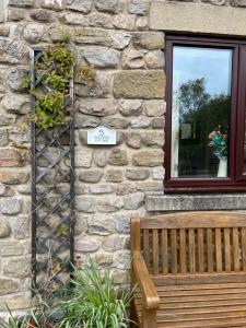 a building with a bench next to a window at Woodside Cottage Grewelthorpe Nr Masham in Grewelthorpe