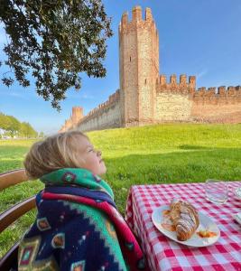 een klein meisje aan een tafel met een bord eten bij Medieval Relais - Top location in Montagnana