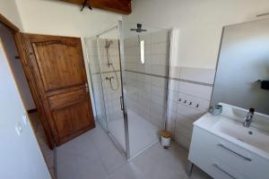 ein Bad mit einer Dusche, einem Waschbecken und einer Tür in der Unterkunft Le Vallon des âmes - Large house for 15 people in Roubion in Névache