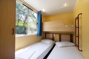 Dos camas en una habitación pequeña con ventana. en Camping Siena Colleverde, en Siena 37 fotos más