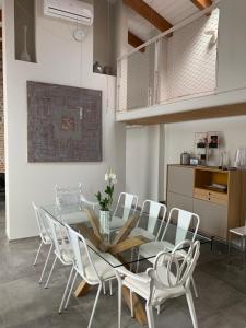 a dining room with a glass table and white chairs at Horse Shoe House in Chiaverano