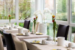 a dining room with tables and chairs with flowers on them at Hotel Rosenstein in Heubach
