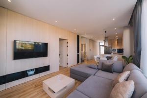 ein Wohnzimmer mit einem Sofa und einem Fernseher an der Wand in der Unterkunft Bliss House Đà Lạt in Da Lat