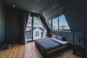 ein Schlafzimmer mit einem Bett und einem großen Fenster in der Unterkunft Bliss House Đà Lạt in Da Lat