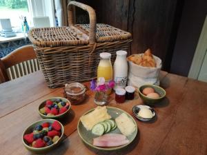 un tavolo con ciotole di cibo e un cesto di pane di Bissems Hofstede a Marle