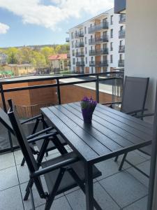 a wooden table on a balcony with a vase of flowers at Sand Apartament Bel Mare Aqua in Międzyzdroje