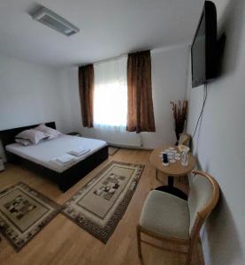 a bedroom with a bed and a table and a tv at Casa UILA in Orşova