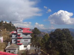 a white building with a red roof on a mountain at A.R . Homestay in Shimla