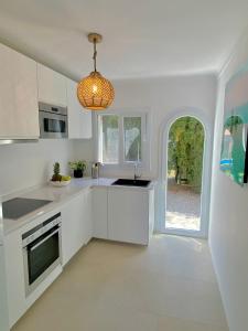 una cocina con armarios blancos y una lámpara de araña en Bonaire Beach House, en Alcudia
