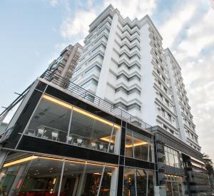 a tall white building with glass windows at HOTEL HI - Xinmin in Chiayi City