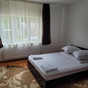 a bedroom with a bed with white sheets and a window at Casa UILA in Orşova