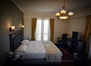 een slaapkamer met een bed, een televisie en een kroonluchter bij Hotel Monec in Ankara