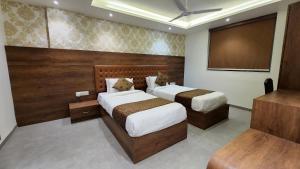 1 dormitorio con 2 camas y TV de pantalla plana en Hotel Nova Pride, en Rajkot