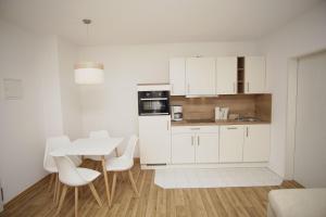 a kitchen with white cabinets and a table and chairs at strandnah mit Terrasse, gratis Nutzung vom AHOI Erlebnisbad und Sauna in Sellin - Strandhaus Mönchgut FeWo06 in Lobbe