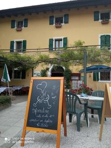 ein Schild an der Tafel vor einem Tisch und Stühlen in der Unterkunft LOCANDA SAN GALLO in Moggio Udinese