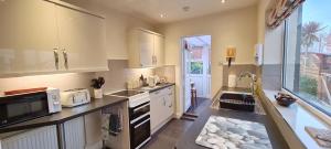 a large kitchen with white cabinets and a sink at Mabel Cottage Sheringham in Sheringham