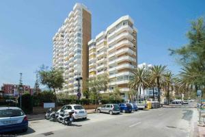 a large building with cars parked in a parking lot at Ronda 3 con enorme terraza soleada in Fuengirola