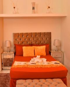 sypialnia z dużym pomarańczowym łóżkiem i 2 stolikami nocnymi w obiekcie Caribbean estate deluxe 2 w mieście Portmore