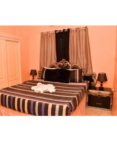 a bedroom with a large bed with a striped blanket at Caribbean estate deluxe 2 in Portmore