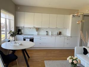 una cocina con armarios blancos y una mesa en una habitación en Koselig leilighet med balkong og sjøutsikt. en Grimstad