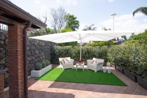 a patio with an umbrella and chairs and grass at Villa Arianna in Acireale