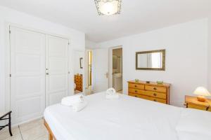 ein weißes Schlafzimmer mit einem großen Bett und einer Kommode in der Unterkunft Villa Rosa in S'Algar