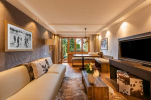 een woonkamer met een bank en een flatscreen-tv bij La Val Hotel & Spa in Brigels