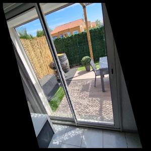 Blick auf eine Terrasse durch eine Glastür in der Unterkunft Maison de vacances Torreilles plage 6 personnes in Torreilles