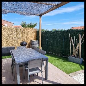 une table et des chaises dans une arrière-cour avec une clôture dans l'établissement Maison de vacances Torreilles plage 6 personnes, à Torreilles