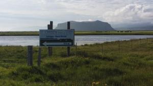 a sign on the side of a lake near a body of water at Mid Hvoll Cottages in Suður Hvoll