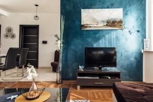 a living room with a tv and a blue wall at Villa Lidija in Omiš