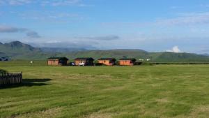 a group of houses in a field with mountains in the background at Mid Hvoll Cottages in Suður Hvoll