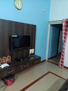 uma sala de estar com televisão e um relógio na parede em Tavaru home stay em Ankola