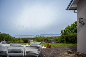 a group of white chairs sitting on a patio at Highfield - 3 Bedroom Holiday Home - Llanmadoc in Llanmadoc